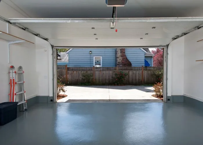 An emptied garage with a clean floor, the door open to the driveway